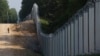 A Polish border guard patrols the area of a newly built metal wall on the border between Poland and Belarus near Kuznica in June 2022.