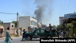 Afghan security personnel secure a road as smoke billows from the site of a suicide attack in Jalalabad on July 31.