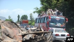 A convoy of local residents travels past the wreckage of a truck as they flee from military operations against Taliban militants in the Naway Kalay area of the Swat Valley.