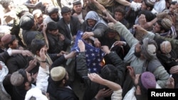 Afghan protesters burn a U.S. flag during a protest in Helmand Province, one of several demonstration hotspots, on February 23.