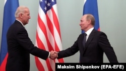 Then-U.S. Vice President Joe Biden (left) shakes hands with then-Russian Prime Minister Vladimir Putin during their meeting in Moscow on March 10, 2011.