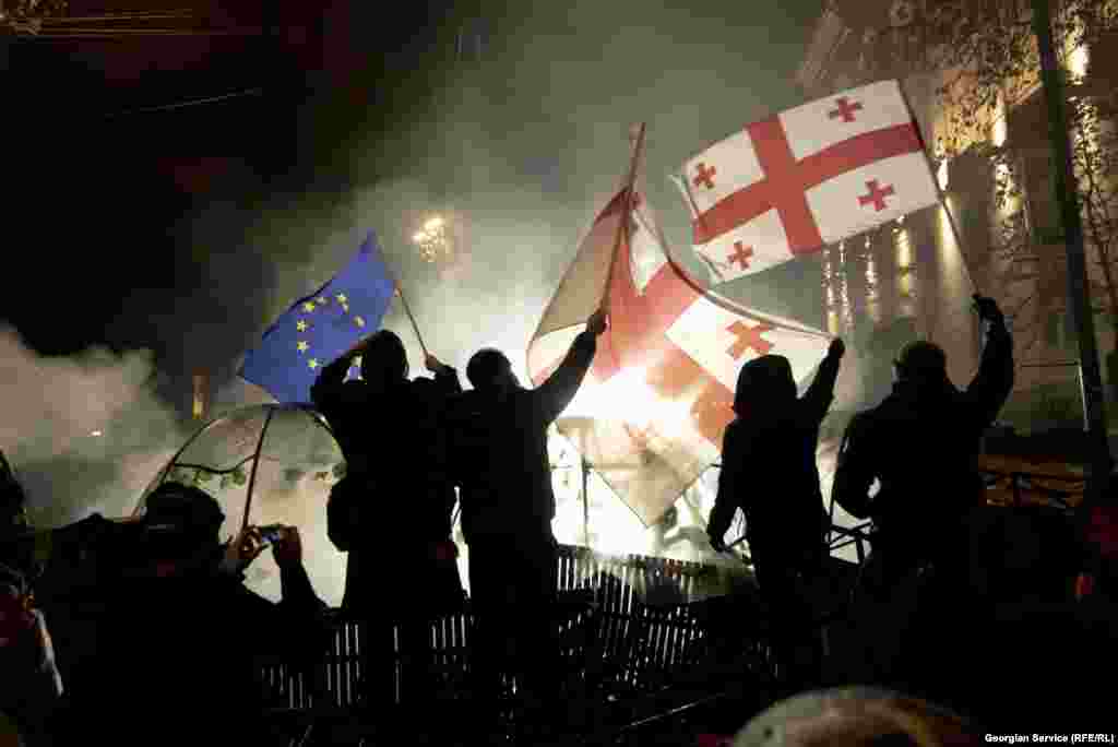 Protesters wave Georgian and EU flags outside the Georgian parliament building on November 29.&nbsp;