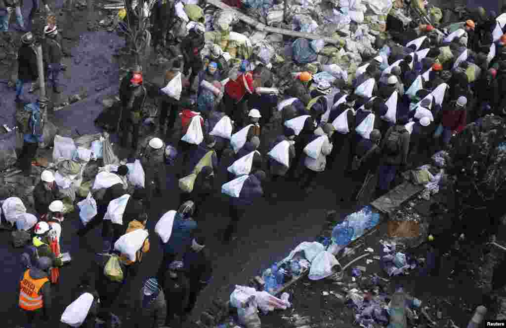 Antigovernment protesters carry bags filled with stones to build barricades around Independence Square.