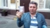 Fikrat Huseynli holds up his Dutch passport outside a Kyiv court on April 16.