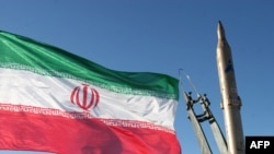 The national flag flutters next to a ground-to-ground Sejil missile before being launched at an undisclosed location in Iran.