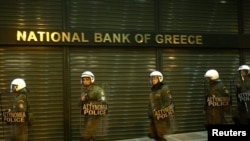  Riot policemen secure a bank branch during an antigovernment rally in Athens last month, fueled by the economic crisis.