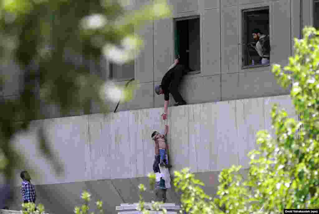 Iranian policemen help civilians fleeing from the parliament building.