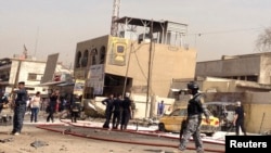 Iraqi security personnel stand at one of the sites of a bomb attack in Baghdad on April 15.