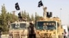 Militant Islamist fighters wave flags as they take part in a military parade in Syria's northern Raqqa province on June 30 to celebrate the announcement of a new Islamic Caliphate by ISIL. 