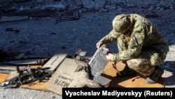 A police officer inspects parts of an unmanned aerial vehicle that Ukrainian authorities say is an Iranian-made Shahed-136 suicide drone at the site of a Russian strike on fuel storage facilities in Kharkiv in October 2022.