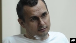 Oleh Sentsov sits behind glass in a cage in a court room in Rostov-on-Don in August 2015.