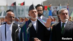 Outgoing Afghan President Hamid Karzai (center) speaks during celebrations to commemorate Afghanistan's 95th anniversary of independence as he is flanked by presidential candidates Abdullah Abdullah (right) and Ashraf Ghani in Kabul on August 19.