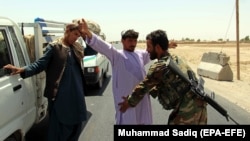 Afghan soldiers search people at a checkpoint on a highway leading to the Maiwind district of restive Kandahar Province on October 19.