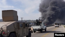 Smoke rises as members of the Syrian forces drive near Latakia, Syria, on March 7.