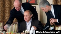 Yevgeny Prigozhin (left), once known as "Putin's chef," serves Russian Prime Minister Vladimir Putin during a dinner outside Moscow in 2011.