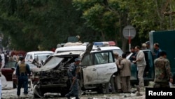 Afghan police investigate the site of a bomb attack against presidential candidate Abdullah Abdullah's motorcade.