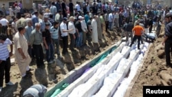 People gather at a mass burial for the victims of a purported artillery barrage from Syrian forces in Houla.