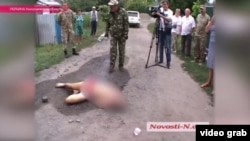 Local residents surround the body of Aleksandr Tsukerman in the middle of a dirt road in the southern village of Krivoye Ozero.