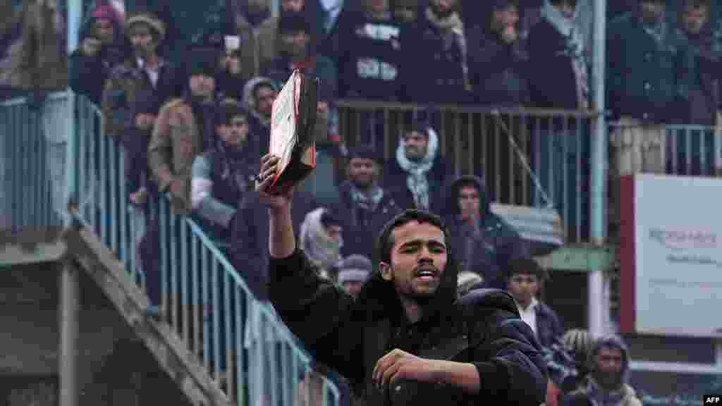 An Afghan demonstrator holds a copy of a half-burned Koran, allegedly set on fire by U.S. soldiers, at the gate of Bagram air base during a protest against Koran desecration at Bagram in February.