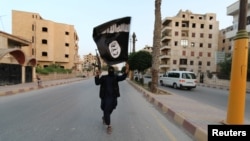 A member of the Islamic State militants waves an IS flag in the Syrian city of Raqqa. (file photo)