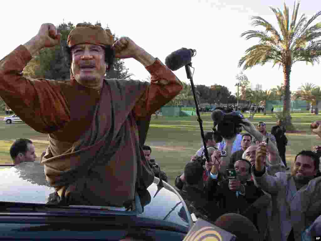 Qaddafi gestures to his supporters in Tripoli on April 10, 2011. Libyan state television aired an audio message from Qaddafi urging loyalists to take arms and fight "traitors and NATO."