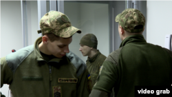 Russian soldier Dmitry Kurashov (center) stands in the Zaporizhzhya courtroom where he is being tried on charges of executing a Ukrainian soldier.