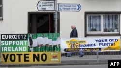 A person walks past a placard on May 30 urging a "no" vote in the referendum on the EU fiscal pact and another sign that announces that the town, Clones, welcomes the old Irish currency, the punt.