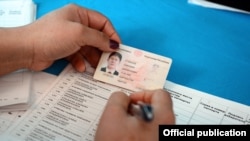 A poll worker checks the identification card of Kyrgyz President Almazbek Atambaev as he voted at a polling station in Bishkek on December 11.