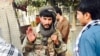 A Taliban fighter talks with residents in the main square after insurgents took control of the strategic northern city of Kunduz.