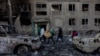 People carry their belongings as they leave their damaged residential building following a strike in Dobropillya, Donetsk region, on March 8.