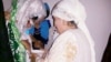 Shahnoza Idrisova (left) and her new mother-in-law perform a wedding ritual during her Internet nuptials last month. 