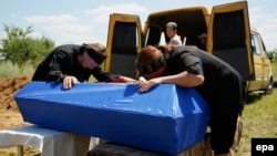 Relatives cry over the coffins of three children killed by a grenade explosion in the Yenakiyeve area near Donetsk earlier this month.