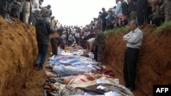 An image released on on April 6 by the opposition Local Coordination Committees in Syria purportedly shows people standing around a mass grave in the town of Taftnaz.