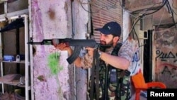 Iranian religious singer Hamid Reza Alimi points a rifle while on a trip to Syria.