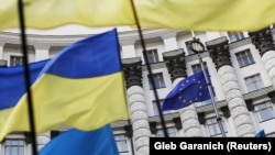 Ukrainian flags and the EU flag are seen during a mass rally in front of the Ukrainian cabinet of ministers building in Kyiv.