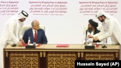 U.S. peace envoy Zalmay Khalilzad (left) and Mullah Abdul Ghani Baradar, the Taliban's top political leader, sign a peace agreement between Taliban and U.S. officials in Doha on February 29, 2020.