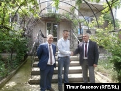 Poluboyarenko (left), Martens (center), and Abazov stand in front of the house that Poluboyarenko offered to the Martenses.