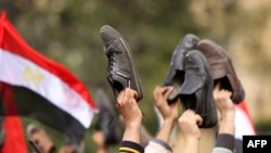 Antigovernment protesters wave their shoes outside a state building in Cairo,