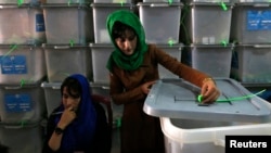 An Afghan election worker cuts a security seal to unlock a ballot box before counting ballot papers during an audit of the presidential runoff in Kabul on August 3.