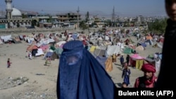 A burqa-clad woman stands by a displacement camp in Kabul on September 17.