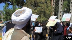 A member of the Taliban watches as Afghan women hold placards during a protest in Herat earlier in September.