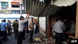 People inspect the damage following two explosions in central Damascus on June 11 that killed at least 14 people.