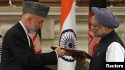 Indian Prime Minister Manmohan Singh (right) greets Afghan President Hamid Karzai in New Delhi