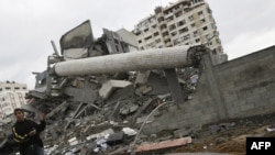 A man in Gaza gestures near an unexploded bomb with the destroyed Palestinian Authority Justice Ministry in the background after Israeli aerial bombing on January 1.