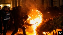 Police attempt to extinguish a fire as supporters of Calin Georgescu protested after Romania's electoral body rejected his candidacy in the presidential election rerun in Bucharest, Romania, Sunday, March 9, 2025. 