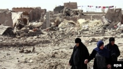 Women in Mosul walk through rubble at the site of a bomb attack in September.