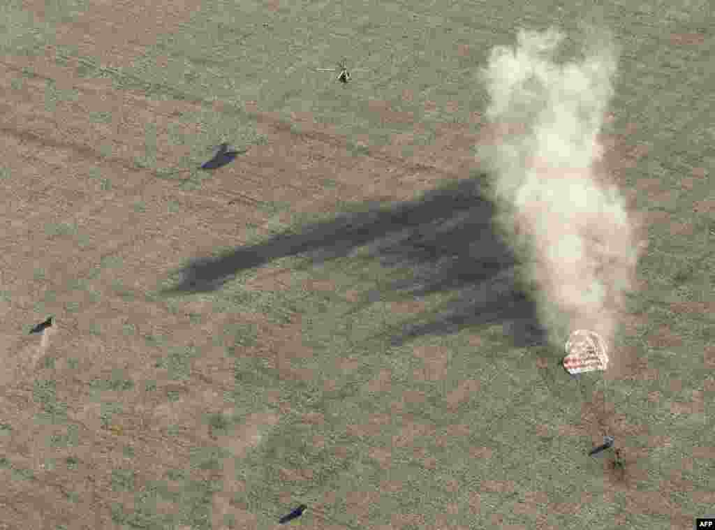 Search-and-rescue teams approach the Soyuz capsule in the moments after touchdown. The Russian space program brings its capsules home on land, as opposed to the sea landings used by the U.S. Apollo program.