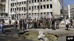 Soldiers stand at the site of twin bombings near the headquarters of the armed forces general staff in Damascus on September 26.