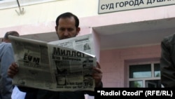 Tajikistan - a man is reading newspaper at the entrance of the court, undated