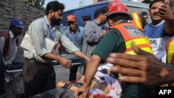 Pakistani volunteers remove a body from the Federal Investigation Agency building after gunmen attacked it in Lahore.